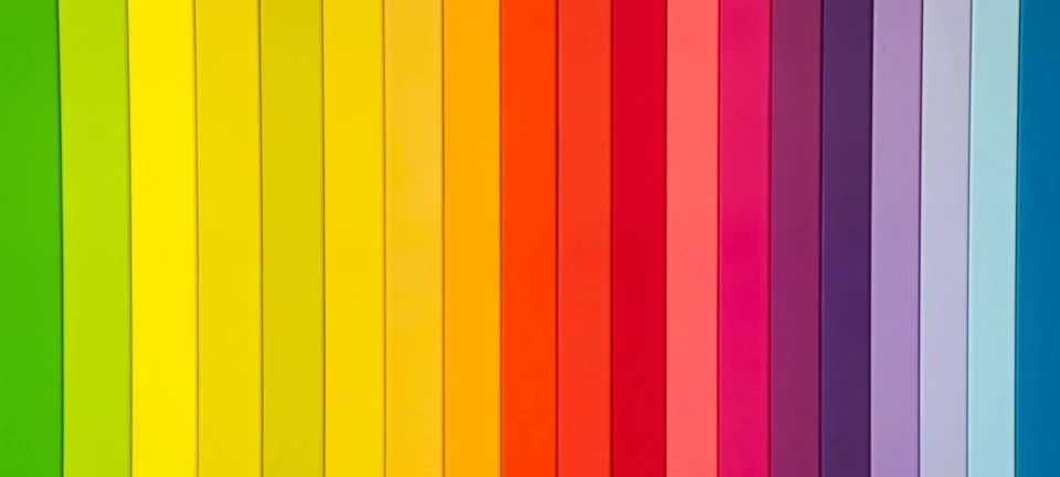 Vertical wooden panels are painted in a vibrant full spectrum of colors arranged in a rainbow gradient.