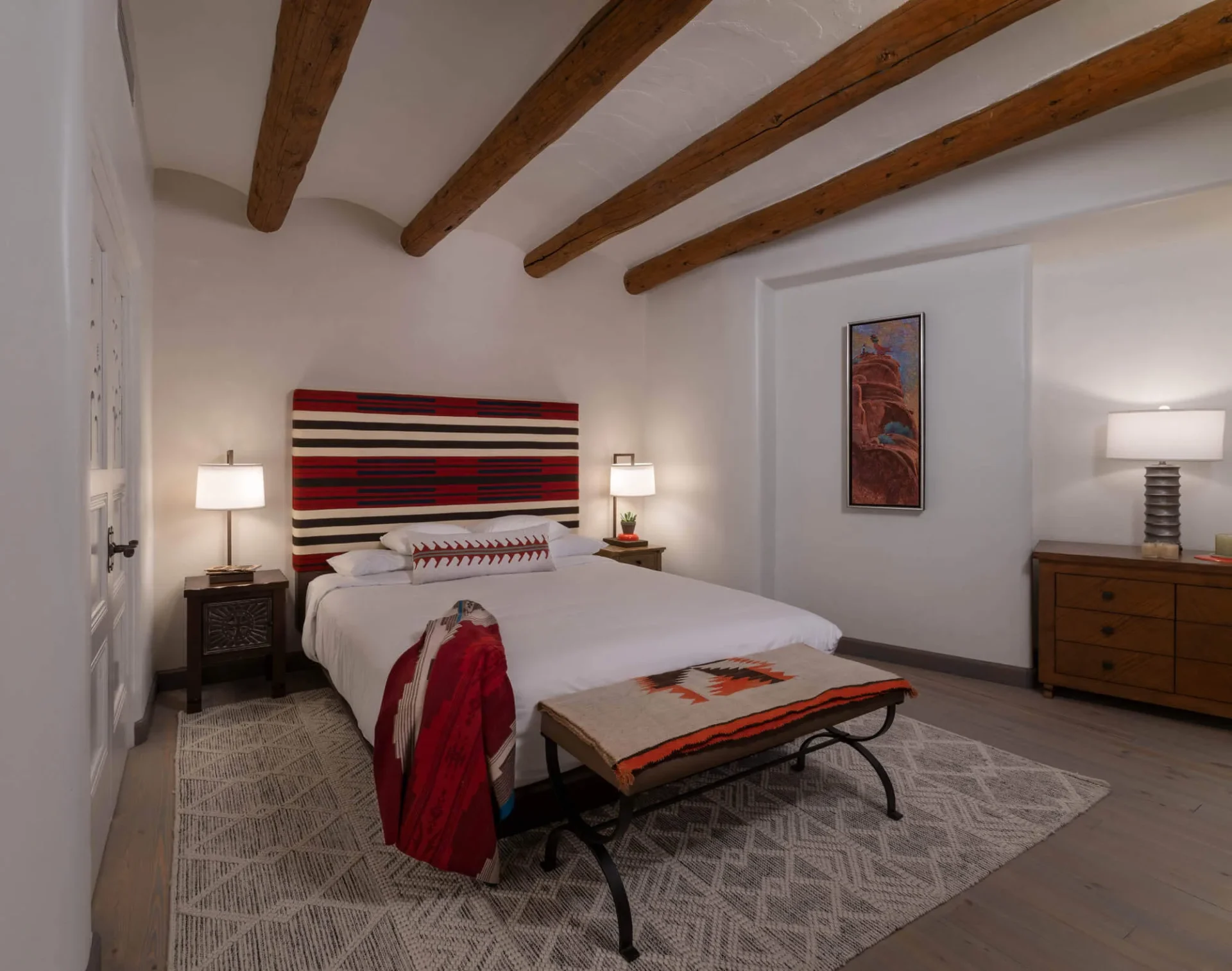 This comfortable hotel room features rustic wooden ceiling beams and colorful Southwestern textile furnishings.