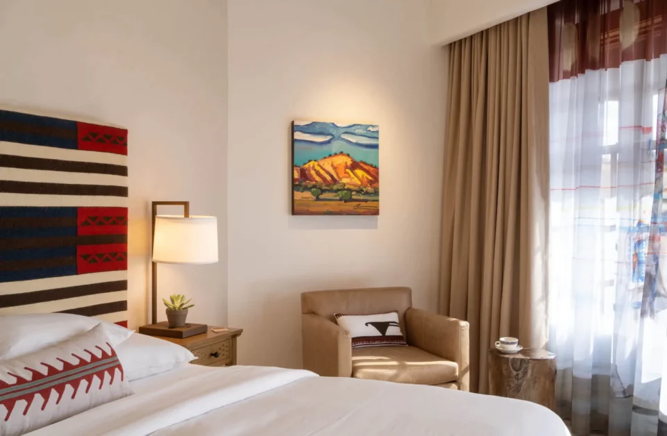 The beautifully designed boutique hotel room offers a luxurious bed, reading light, and Southwestern artwork.