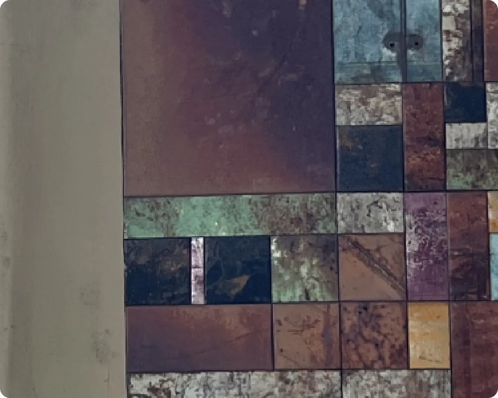 An intricate geometric wall design utilizes varied rectangular tiles in earthy green, maroon, and brown tones.