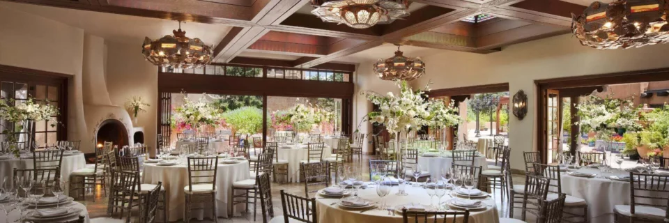 This spacious banquet hall is decorated with elegant white floral centerpieces and formal place settings for a grand.