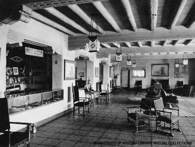The historic hotel common area features traditional Southwestern Viga ceilings, heavy wooden furniture, and a display.
