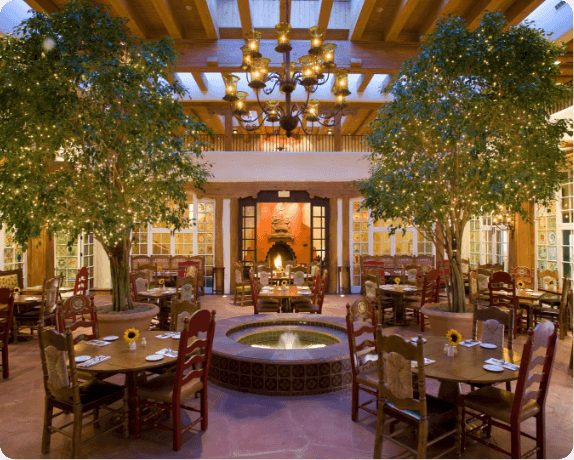 The beautiful downtown Santa Fe restaurant features an indoor fountain and large potted trees decorated with lights.