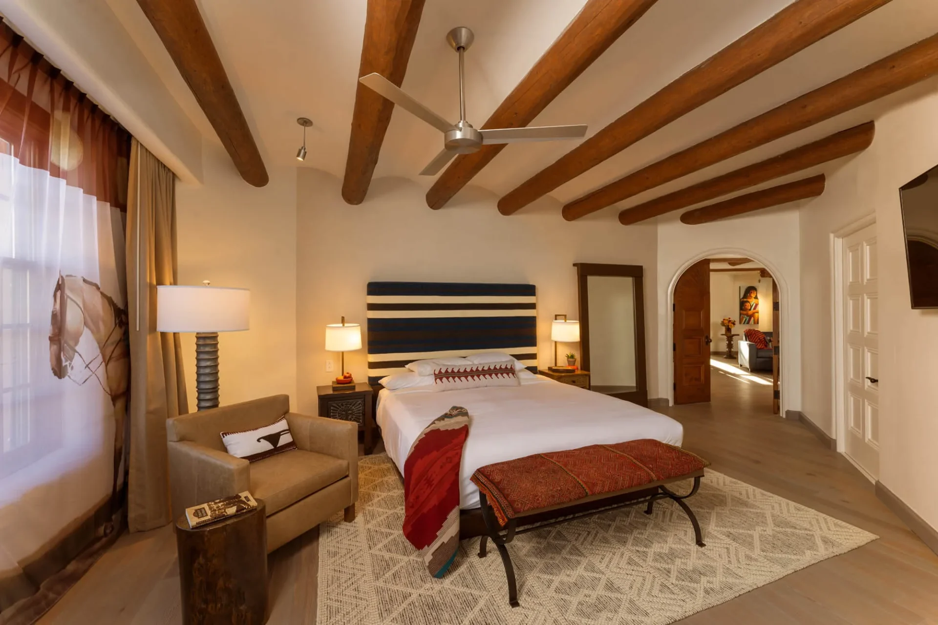 This luxurious hotel suite showcases Southwestern decor, a striped headboard, and wooden ceiling vigas.