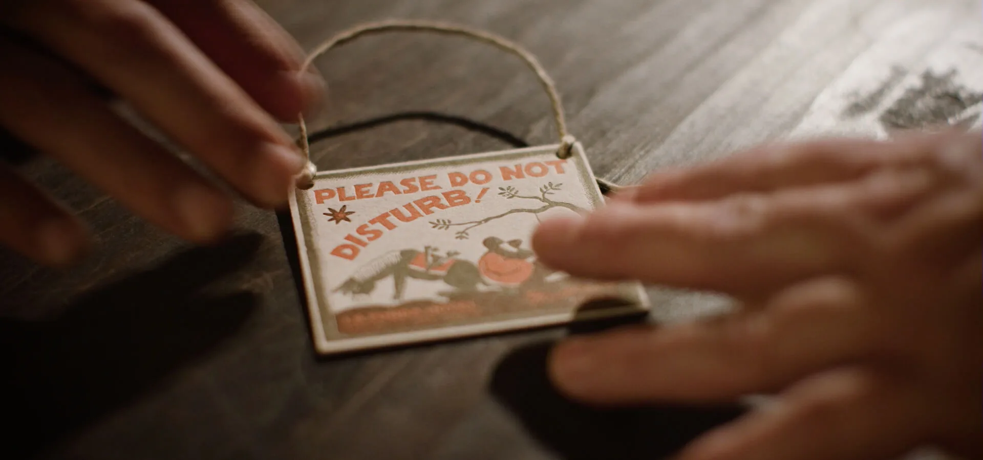 Hands hold a decorative Please Do Not Disturb sign, ensuring privacy within the charming hotel rooms.
