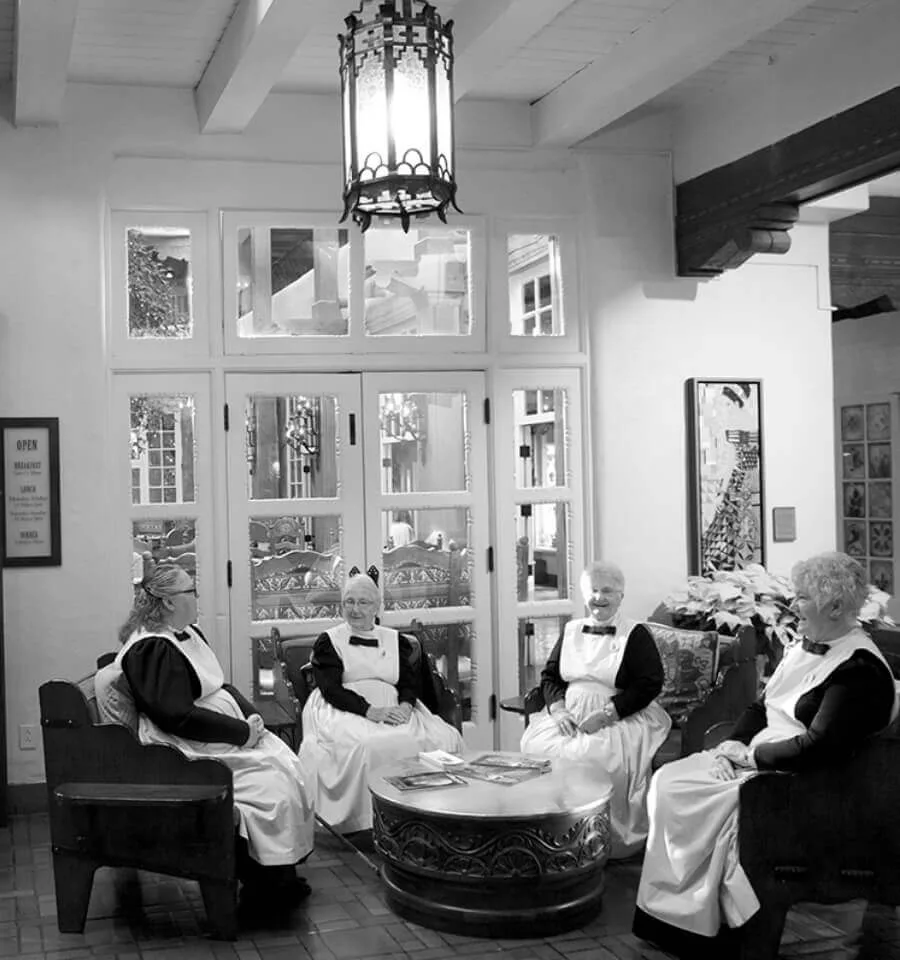 Four women in traditional attire are sitting together around a carved wooden table in the historic boutique hotel lobby.