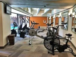 Various exercise machines are set up in the hotel's modern workout room next to windows overlooking the outdoor.