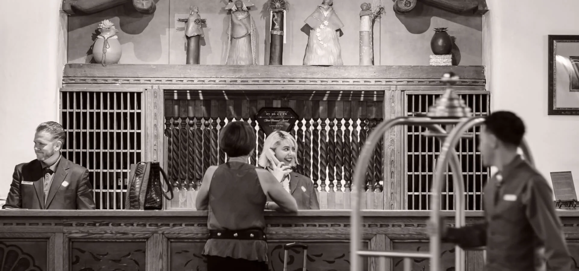 A smiling clerk assists a guest at the ornate front desk of the historic boutique hotel.