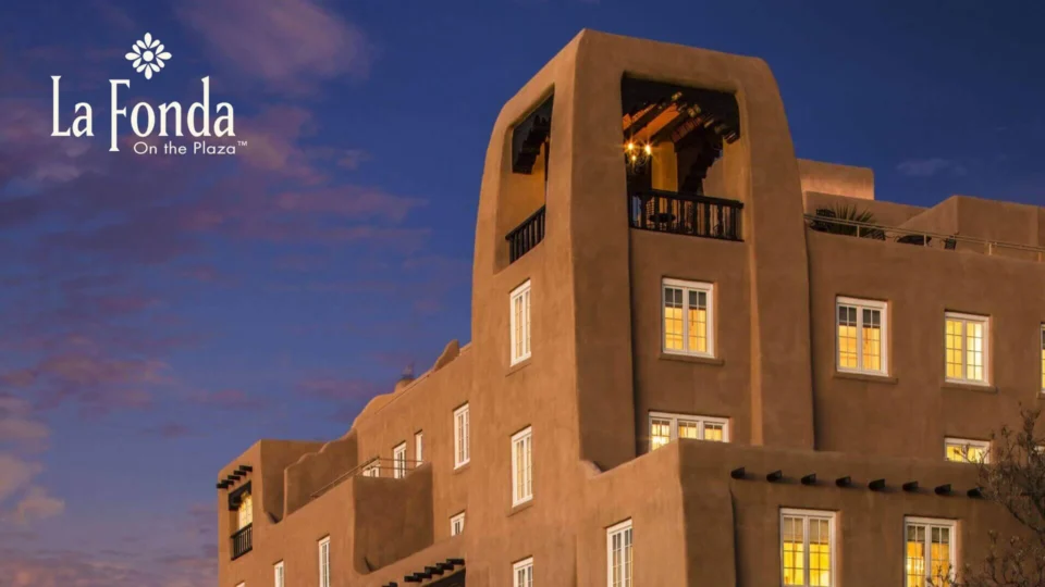 The beautiful adobe exterior of the boutique hotel is illuminated under the twilight sky.