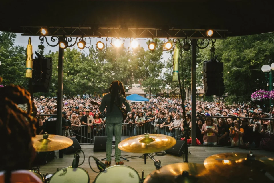 An artist performs on stage for a large, energetic audience at a vibrant live music event.