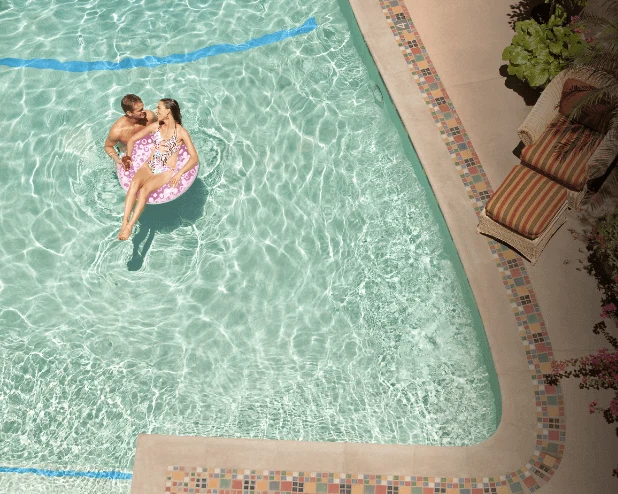 A couple enjoys the relaxing water of the hotel swimming pool on a float.