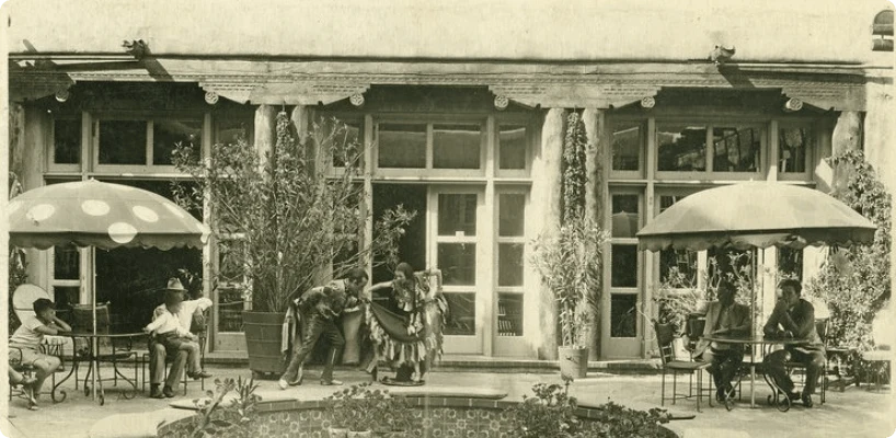A vintage photograph shows two dancers performing for seated patrons on an outdoor patio.