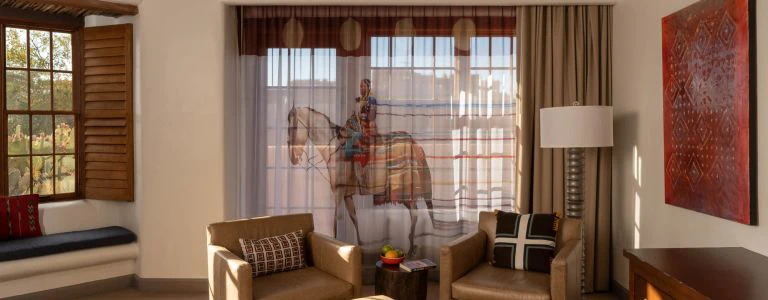 A luxurious hotel suite sitting area showcases custom horse drapery, leather chairs, and authentic Southwestern decor.