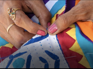 A Person Sewing A Colorful Piece Of Fabric