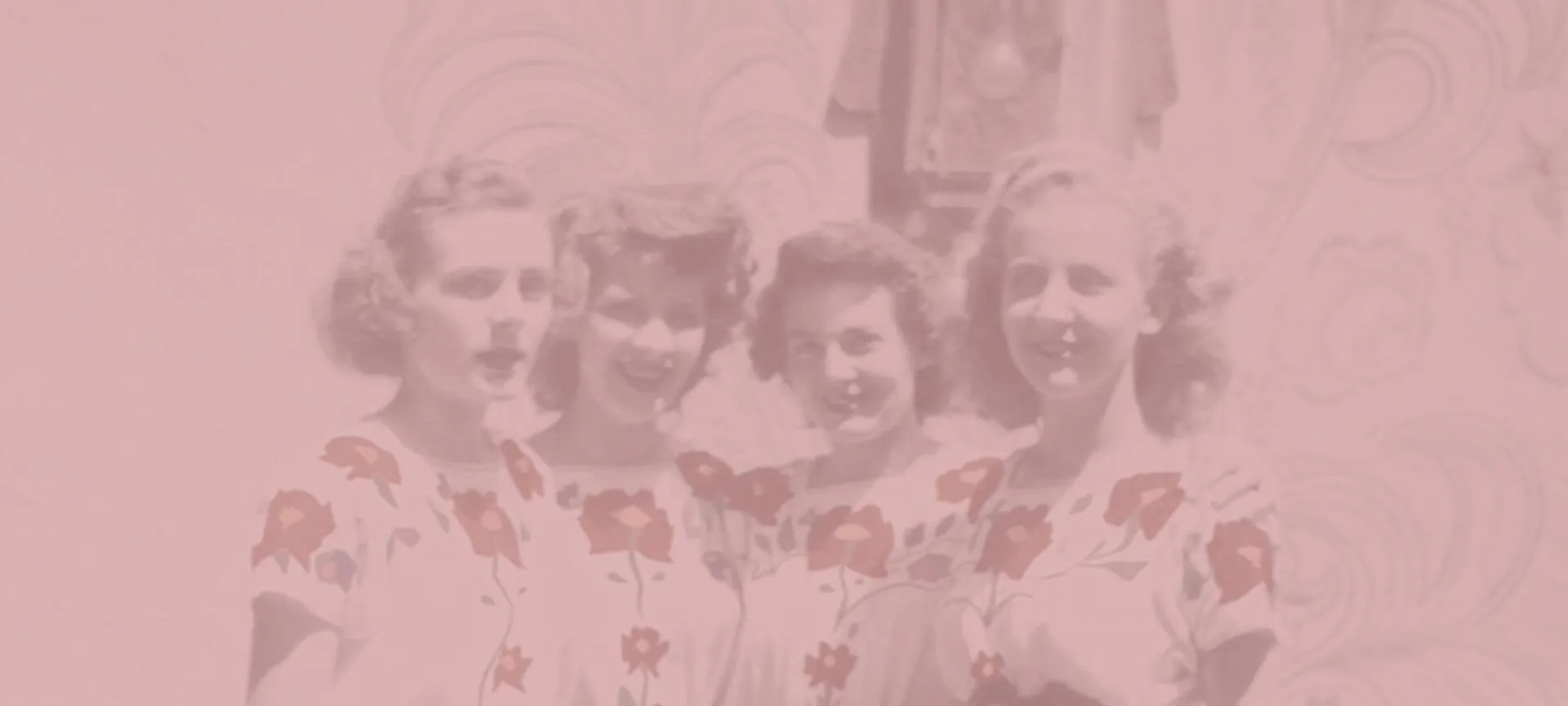 Four smiling women in floral print dresses are visible in this heavily pink-faded archival photograph.