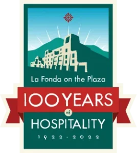 A commemorative badge celebrates 100 years of hospitality at La Fonda on the Plaza, featuring the historic building.