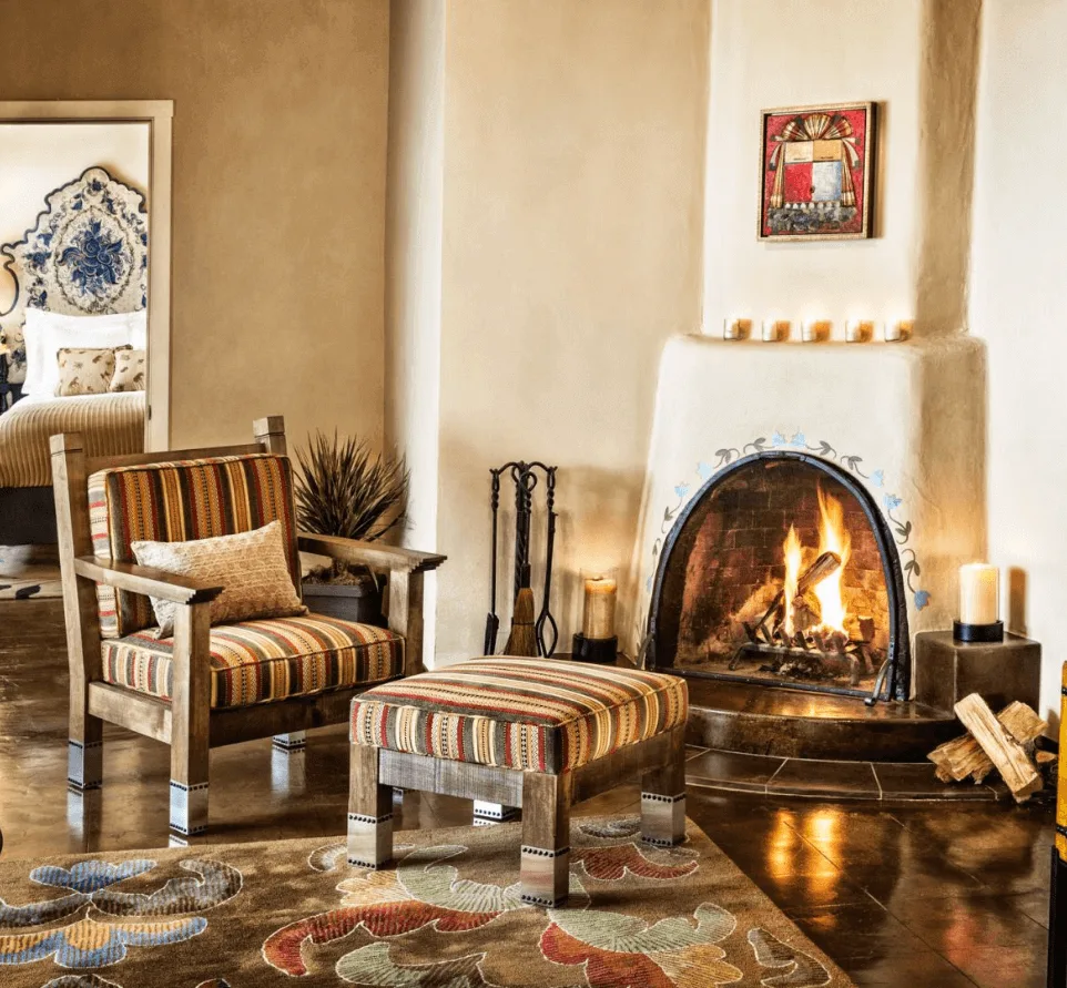 An adobe fireplace warms a comfortable armchair and ottoman in a luxurious hotel suite.