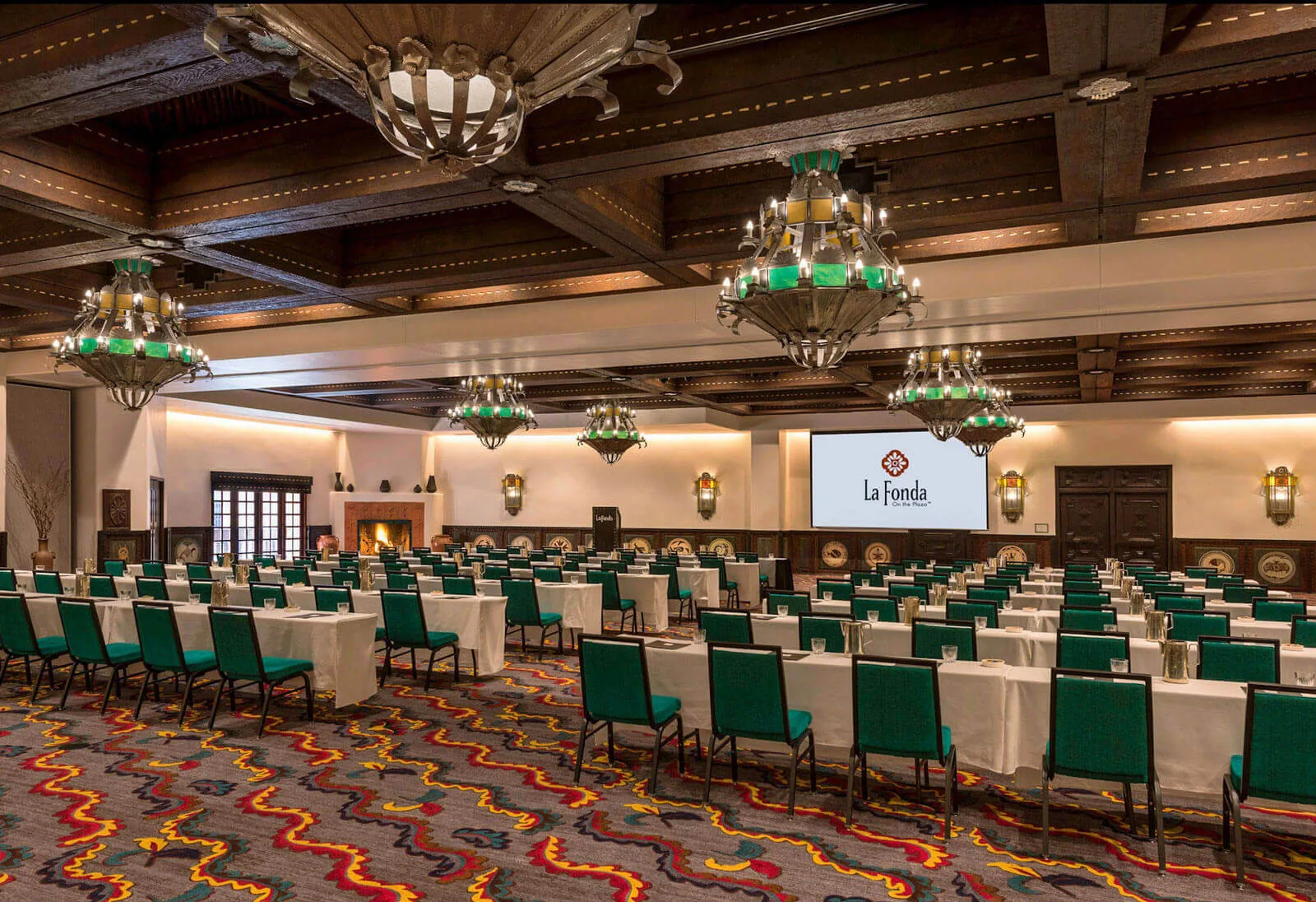 The expansive ballroom is arranged in classroom style with teal chairs and ornate Southwestern light fixtures.