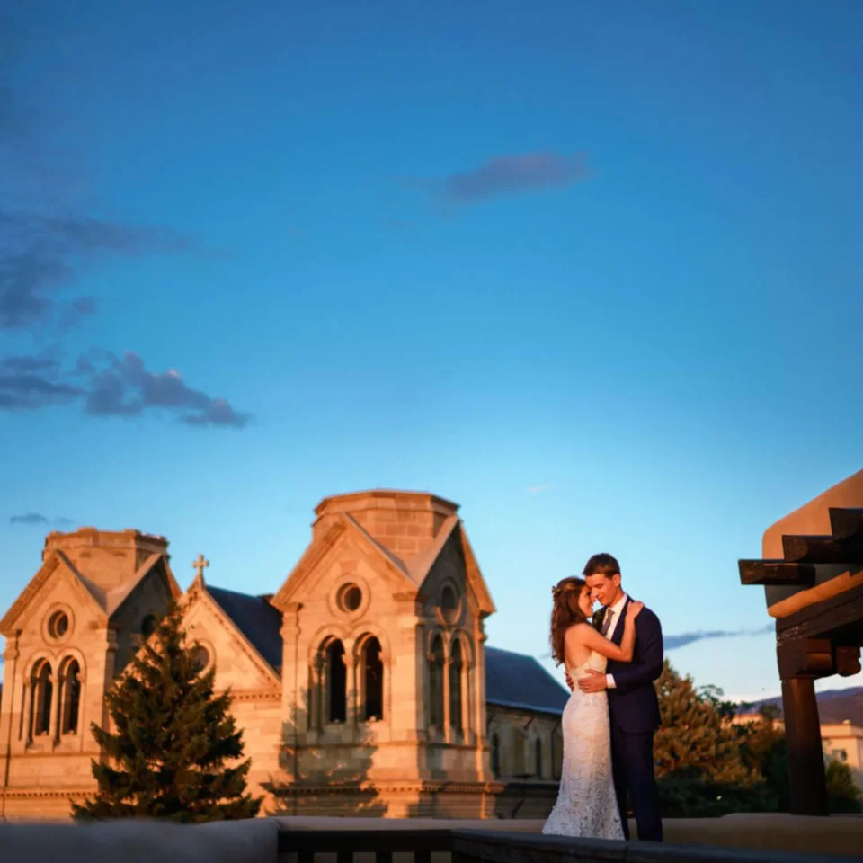 A newlywed couple embraces on a rooftop at sunset, capturing a romantic moment at the event space.
