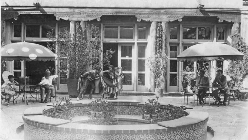 Dancers perform in the historic courtyard, entertaining patrons seated at the outdoor restaurant tables.