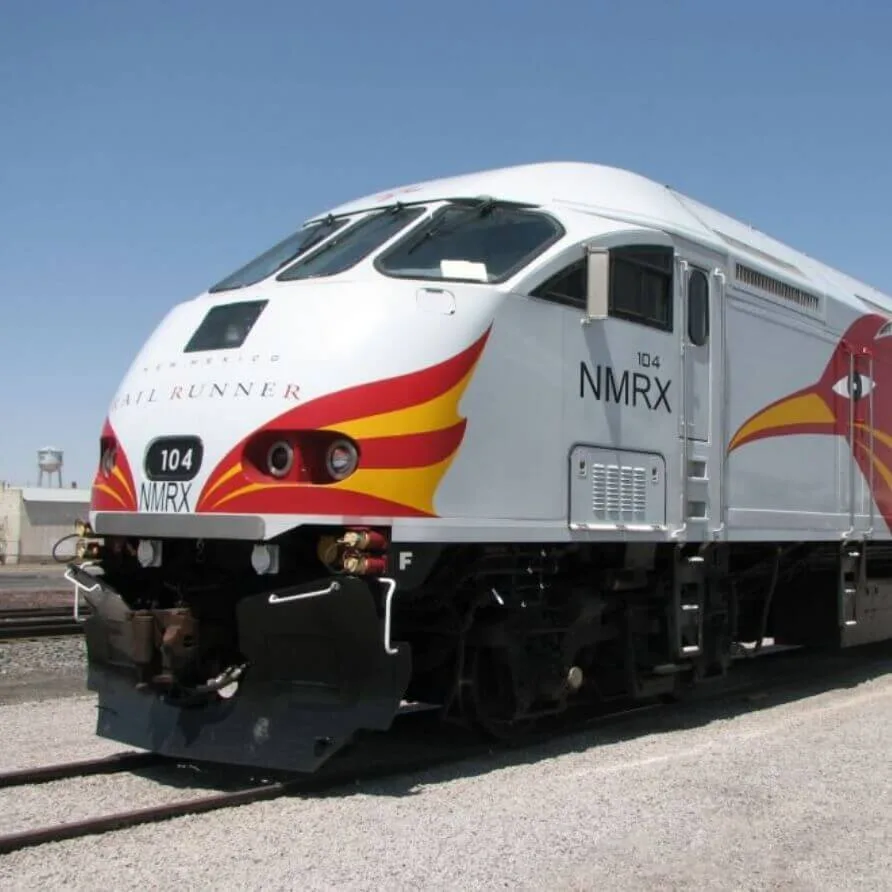 A striking white and gray commuter train engine with bold red and yellow striping is parked on the tracks.