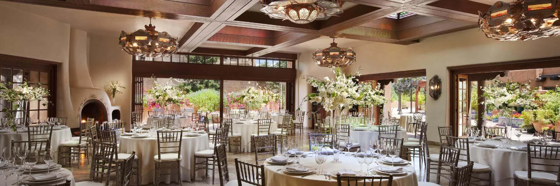 This spacious banquet hall is decorated with elegant white floral centerpieces and formal place settings for a grand.
