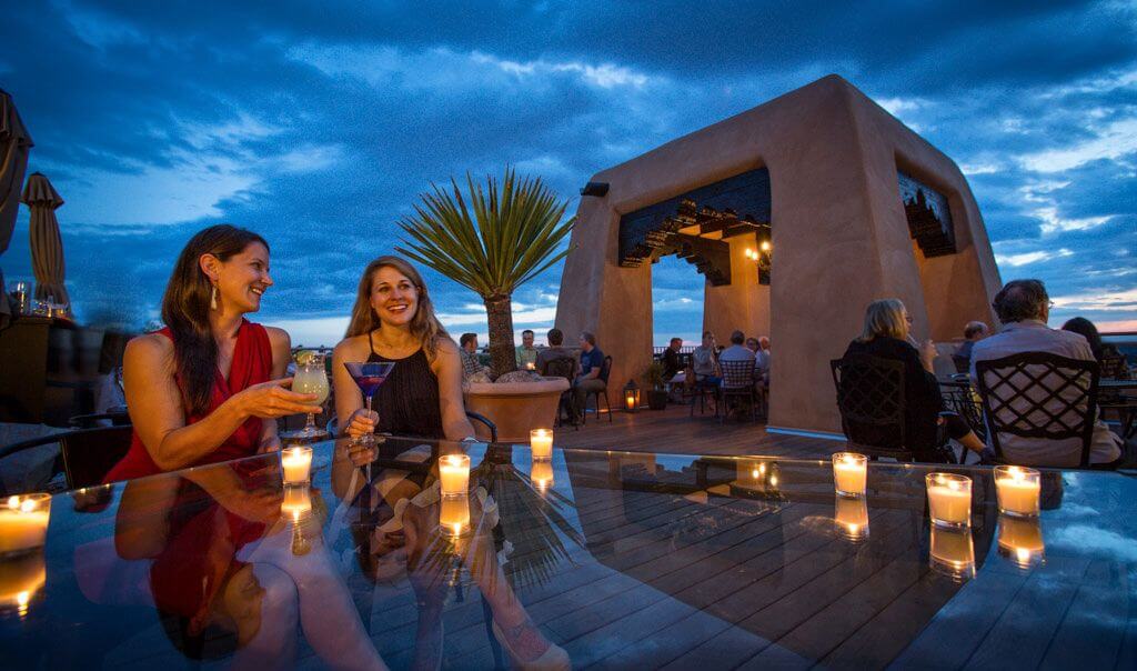two women sitting at a table in a pool with candles and wine glasses
