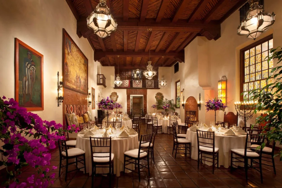 A beautifully decorated santa fe ballroom features dark wood ceilings and large paintings on the walls.