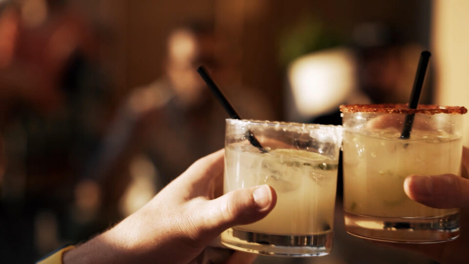 Guests enjoy cocktails, clinking glasses at the rooftop bar.