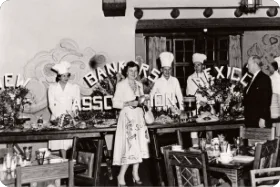 Chefs and a guest stand in a historical banquet hall event setup for the New Mexico Bankers Association.