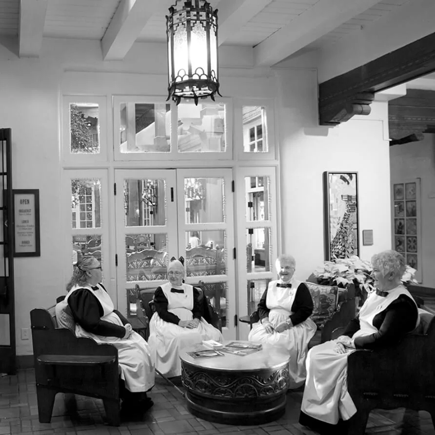 Four staff members in historic uniforms sit together in the beautiful boutique hotel lobby.
