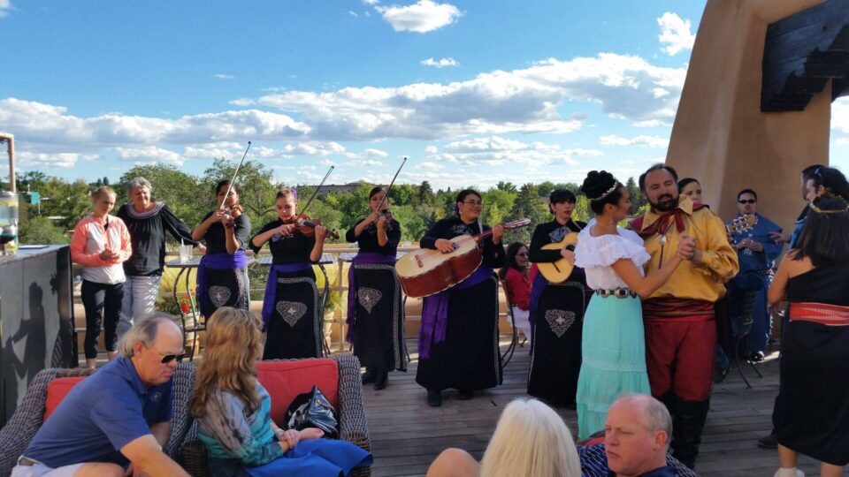 Guests enjoy a lively atmosphere with live music and dancing on a sunny outdoor rooftop patio.
