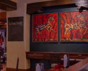 The inviting interior of this lounge, one of the downtown Santa Fe restaurants, displays vibrant artwork and cozy booth.