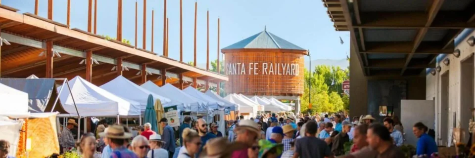 Shoppers browse vendor tents at a crowded outdoor market, utilizing local event spaces under a bright sky.