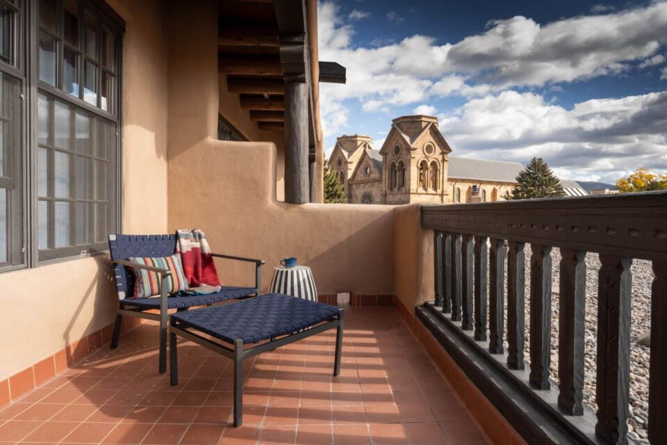 A private outdoor patio, featuring dark woven seating and a terracotta floor, offers views of the old church.