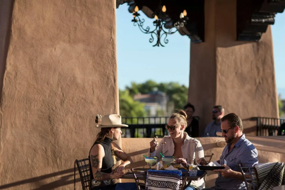 Three guests share food and margaritas while dining on the vibrant outdoor terrace of the restaurant.