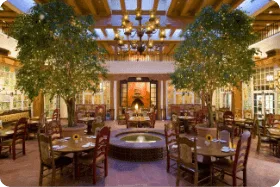 This stunning indoor restaurant setting features two large trees, a central fountain, and Southwestern architecture.