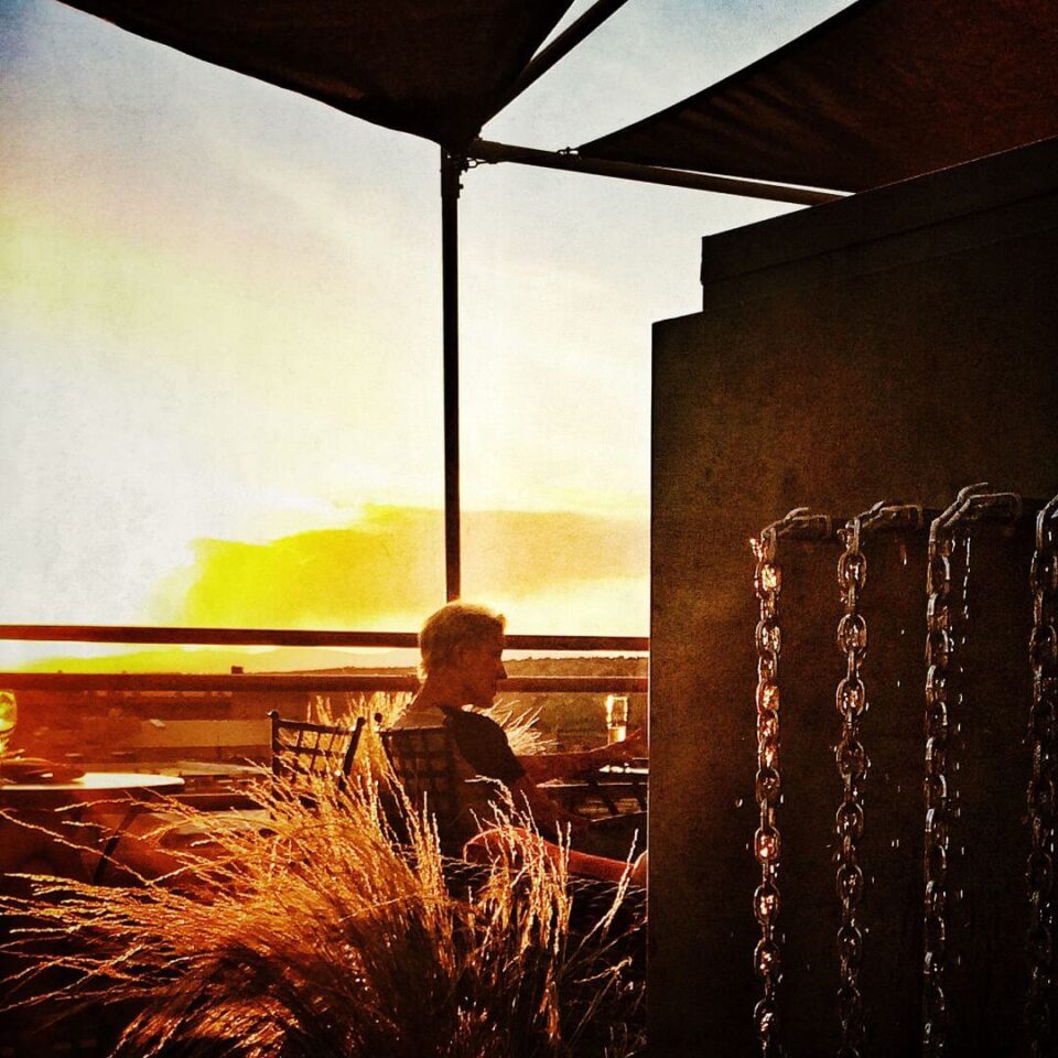 An individual sits on a chair watching the brilliant golden sunset from the rooftop bar.