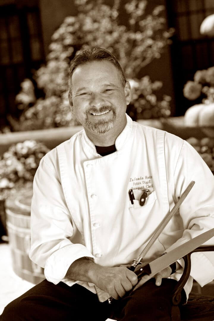 Chef Peter Vigil, the banquet chef, smiles while holding cutlery outside the event space.