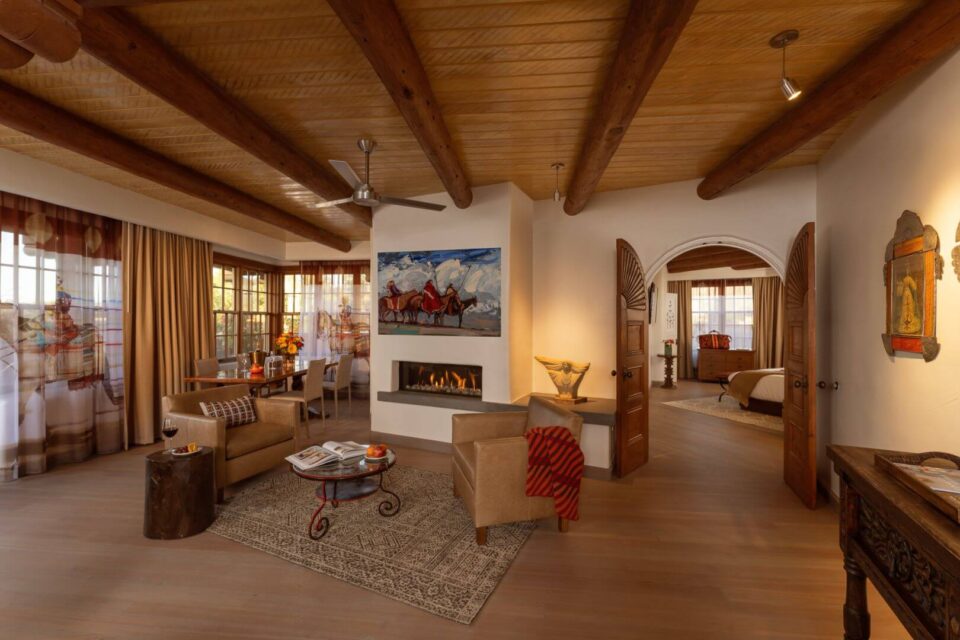 This elegant living space of a hotel suite features a modern fireplace, leather furniture, and a dining area.