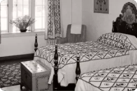 A vintage black and white image of classic twin Santa Fe hotel rooms decorated with southwestern textiles.
