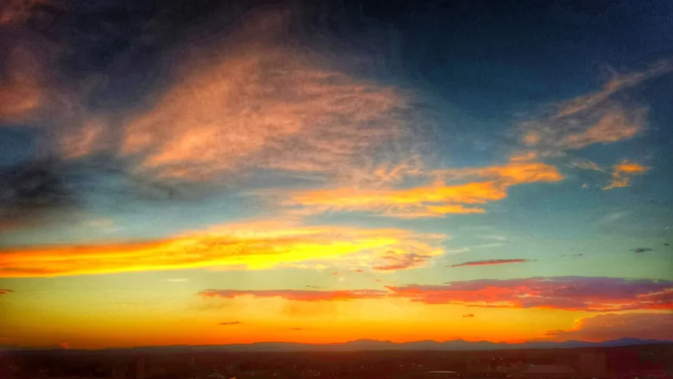 The dramatic sunset sky displays brilliant streaks of yellow, orange, and deep coral above the distant horizon.