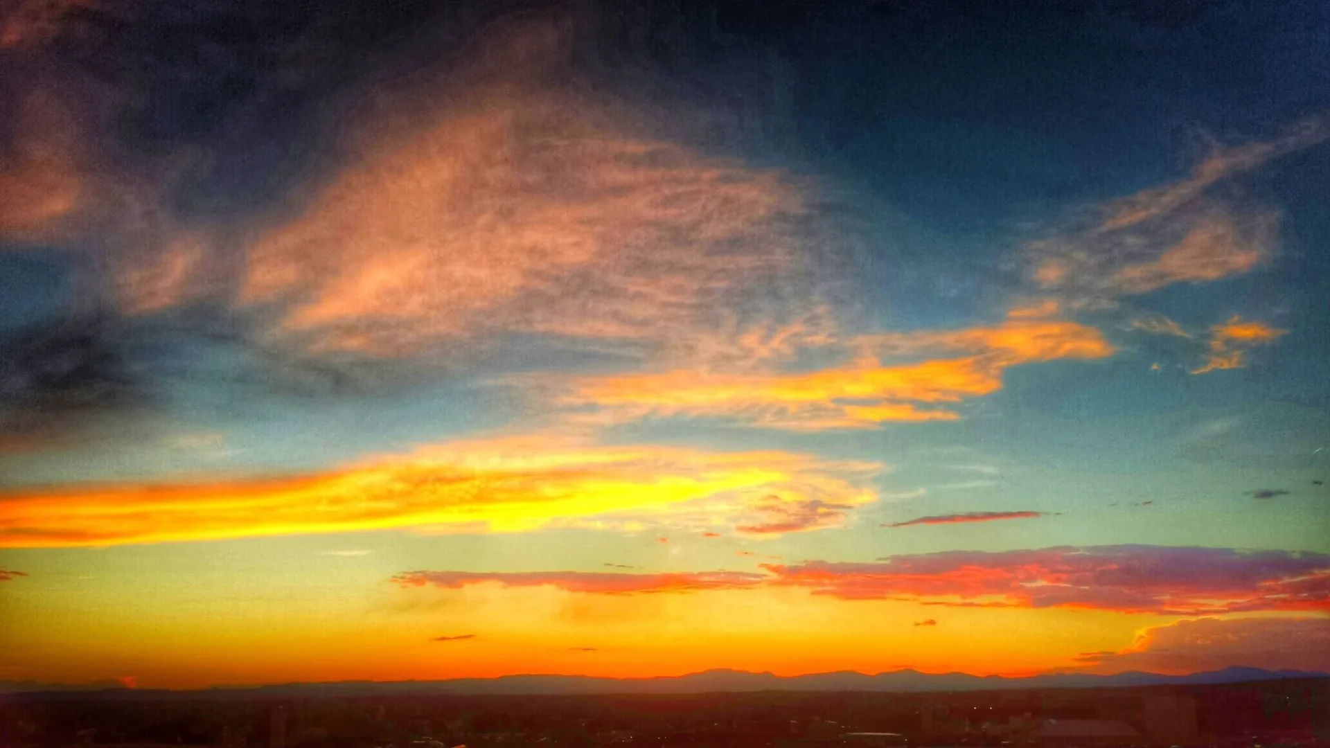 The dramatic sunset sky displays brilliant streaks of yellow, orange, and deep coral above the distant horizon.