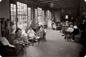 Guests socialize in a bright, historic sunroom, showcasing an early use of the event space.