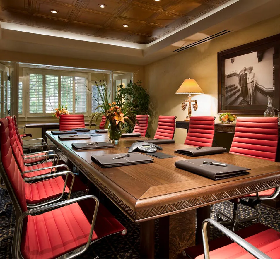 This small event space features a long carved conference table and twelve modern red chairs.