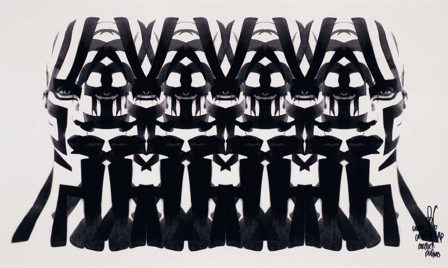A striking black and white abstract print shows a symmetrical pattern of repeated, stylized human faces and figures.