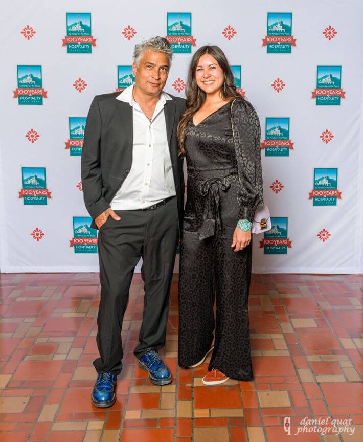 Two formally dressed guests pose on the terracotta tile floor of the banquet hall.