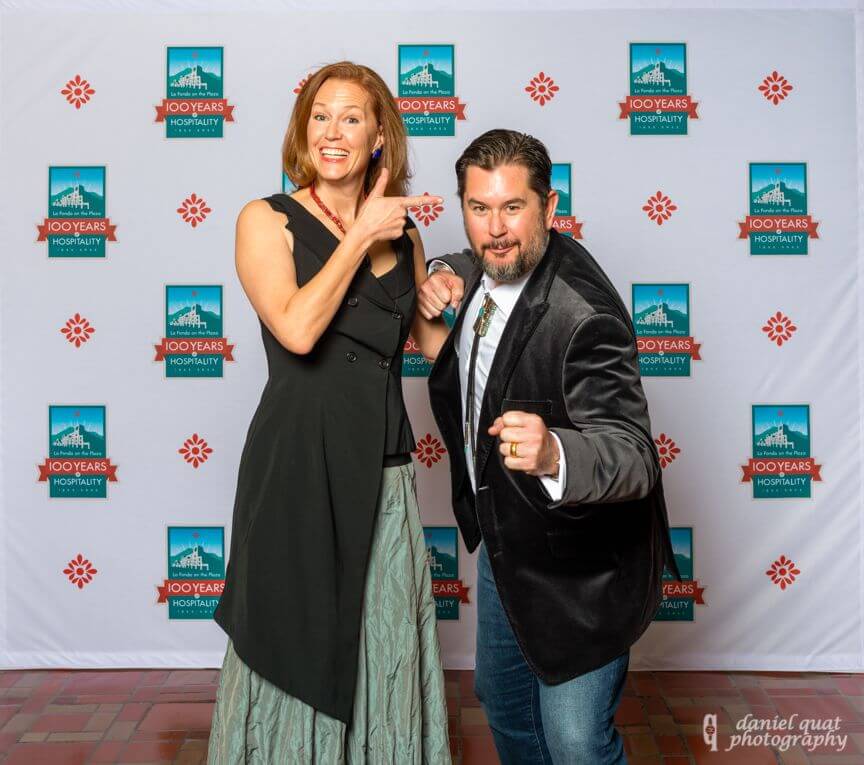 A smiling woman and man enthusiastically pose in front of a step-and-repeat banner at one of the hotel's event spaces.