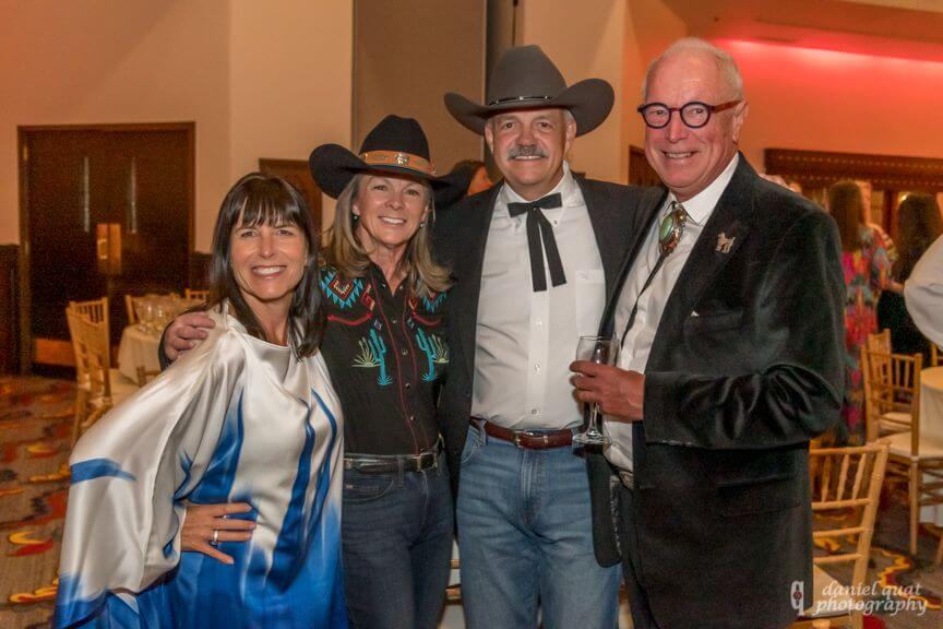 Four smiling guests dressed in western and formal attire pose together at a fun celebration in the hotel event spaces.