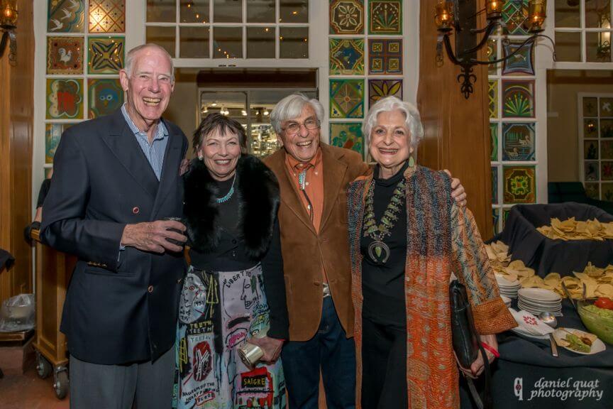 Four guests smile brightly while attending a catered reception held within a decorated event space.